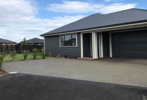 Exposed aggregate driveway with a channel drain. 
Asphalt vehicle crossing from the driveway to the road.